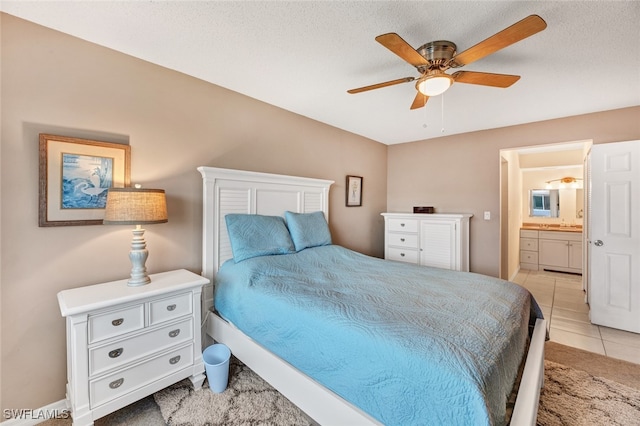 bedroom featuring a textured ceiling, ensuite bath, ceiling fan, and light tile patterned floors