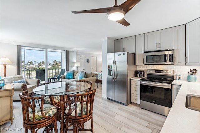 kitchen featuring gray cabinetry, ceiling fan, tasteful backsplash, appliances with stainless steel finishes, and light wood-type flooring