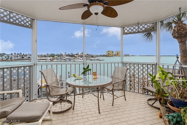 sunroom / solarium with ceiling fan and a water view