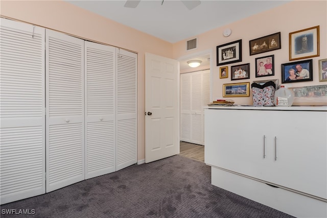 unfurnished bedroom with a closet, dark carpet, and ceiling fan