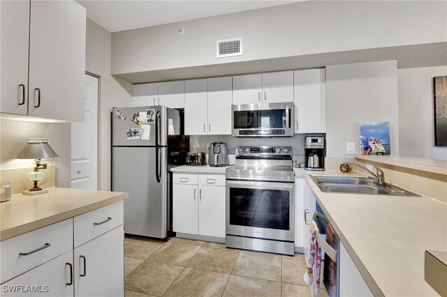 kitchen with sink, stainless steel appliances, white cabinetry, and light tile patterned floors