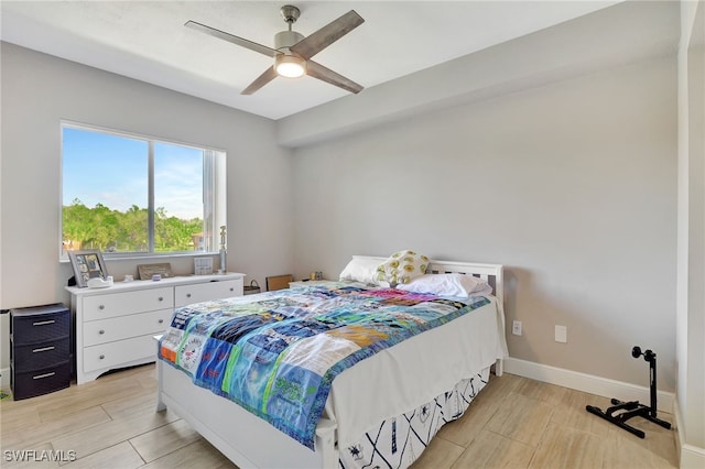 bedroom with light wood-style floors, baseboards, and a ceiling fan