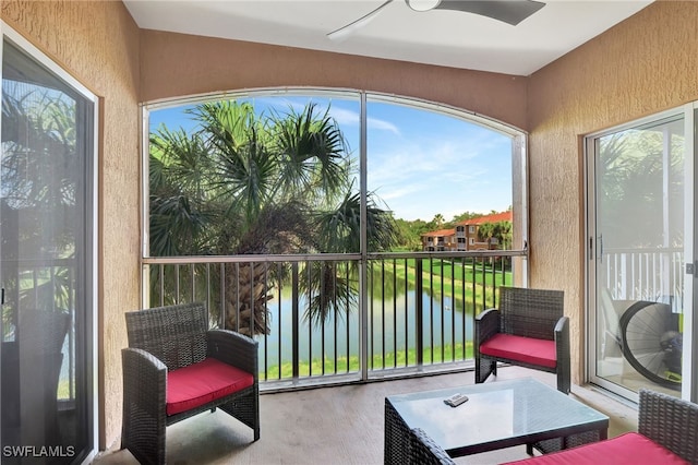 sunroom with ceiling fan and a water view