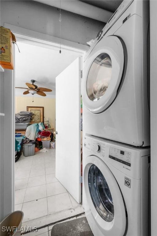 laundry area featuring ceiling fan, light tile patterned floors, and stacked washer and clothes dryer