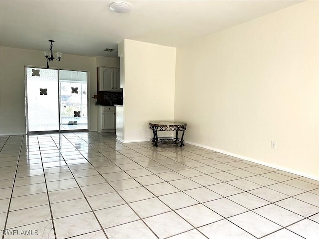 spare room with light tile patterned flooring and a notable chandelier