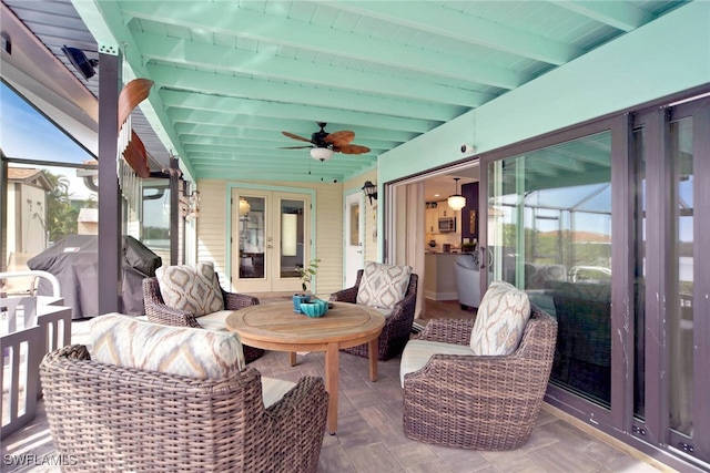 sunroom / solarium featuring beamed ceiling, plenty of natural light, ceiling fan, and french doors