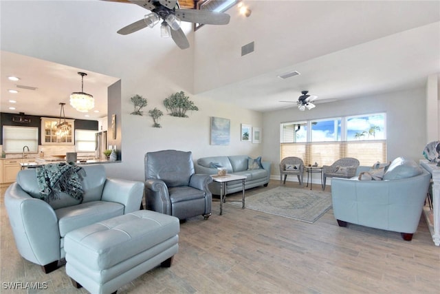 living room with light hardwood / wood-style flooring, ceiling fan with notable chandelier, and sink