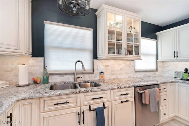 kitchen featuring stainless steel dishwasher, light stone countertops, sink, and tasteful backsplash