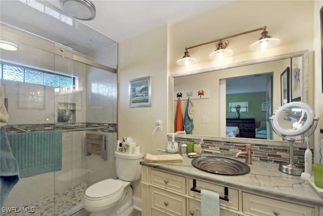 bathroom featuring decorative backsplash, vanity, toilet, and a shower with door