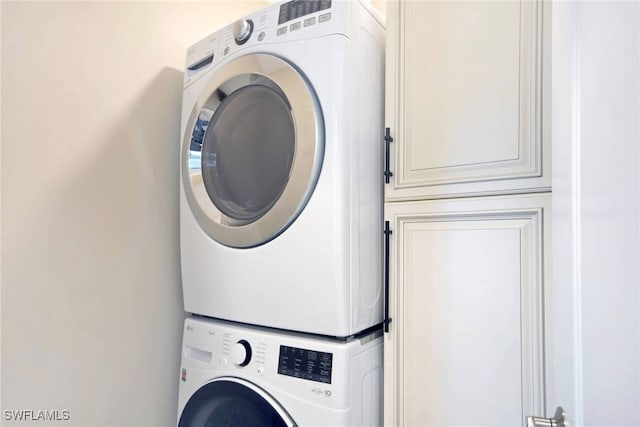 washroom featuring cabinets and stacked washing maching and dryer