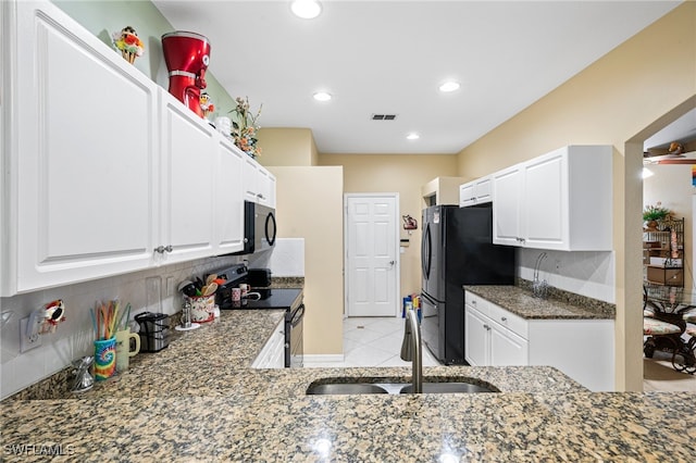 kitchen featuring dark stone countertops, white cabinetry, sink, and black appliances