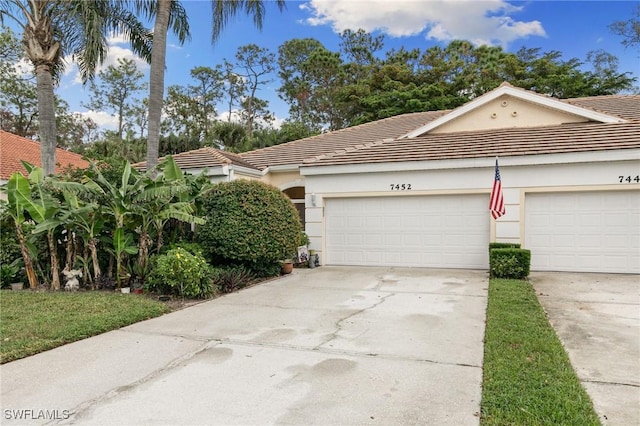 7452 Berkshire Pines Dr, Naples, FL 34104 - view of front of property featuring concrete driveway, stucco siding, a tiled roof, and a garage