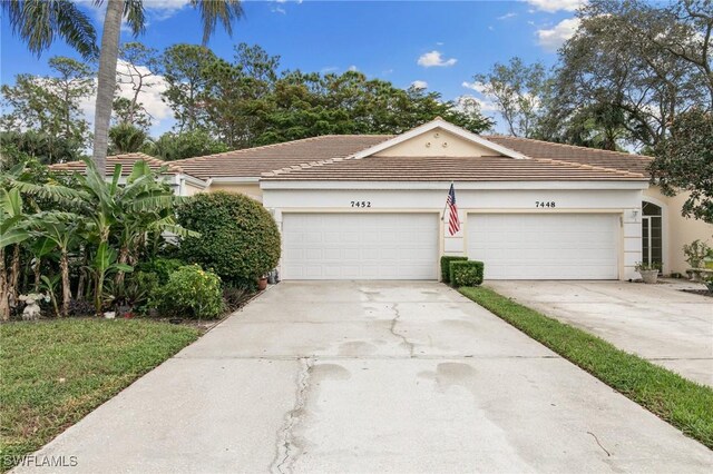 7452 Berkshire Pines Dr, Naples, FL 34104 - view of front facade with stucco siding, concrete driveway, a tile roof, and a garage