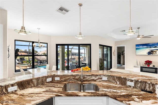 kitchen featuring white cabinets, ceiling fan with notable chandelier, sink, and decorative light fixtures