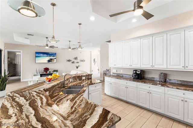 kitchen with light hardwood / wood-style floors, white cabinetry, sink, a raised ceiling, and pendant lighting