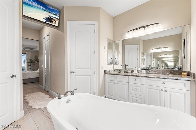 bathroom with hardwood / wood-style floors, vanity, and a tub