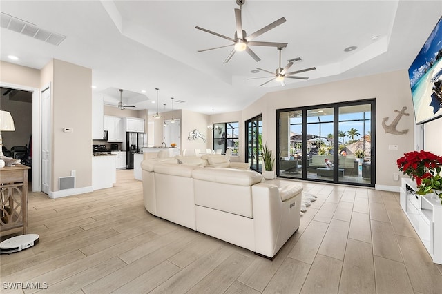 living room featuring light wood-type flooring and a tray ceiling