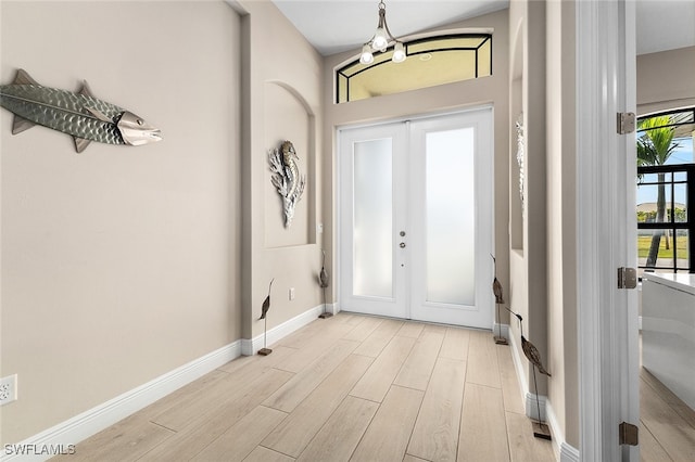 foyer with french doors, a notable chandelier, and light hardwood / wood-style floors