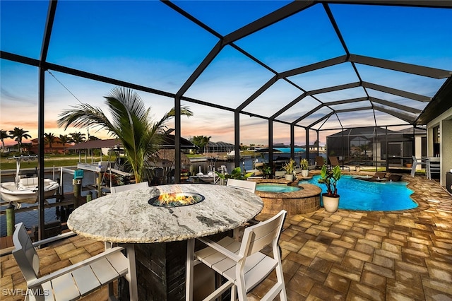 patio terrace at dusk featuring a lanai and a pool with hot tub