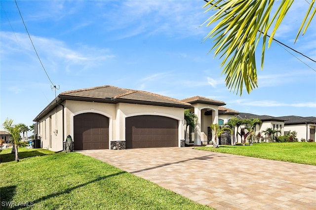 mediterranean / spanish-style house with central AC unit, a garage, and a front yard