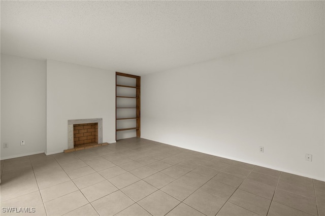 unfurnished living room with light tile patterned floors, a fireplace with raised hearth, and a textured ceiling