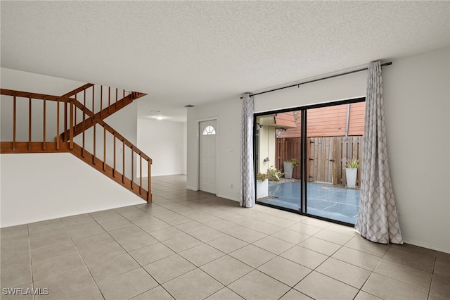 unfurnished room with light tile patterned floors, a textured ceiling, and stairs