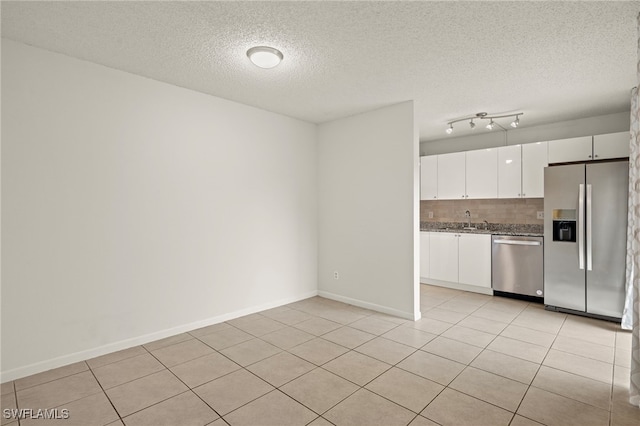 kitchen featuring light tile patterned floors, appliances with stainless steel finishes, white cabinetry, and decorative backsplash