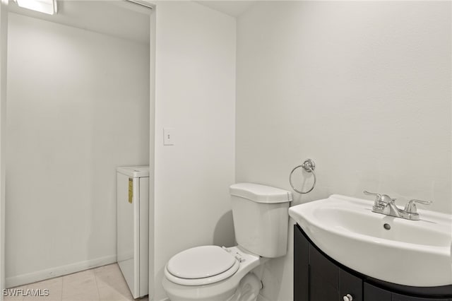 half bathroom with baseboards, toilet, washer / clothes dryer, tile patterned flooring, and vanity