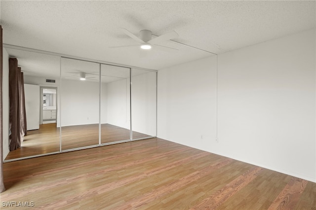 unfurnished bedroom featuring a closet, a textured ceiling, and wood finished floors