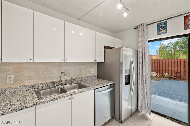 kitchen with light tile patterned floors, appliances with stainless steel finishes, a sink, and white cabinets