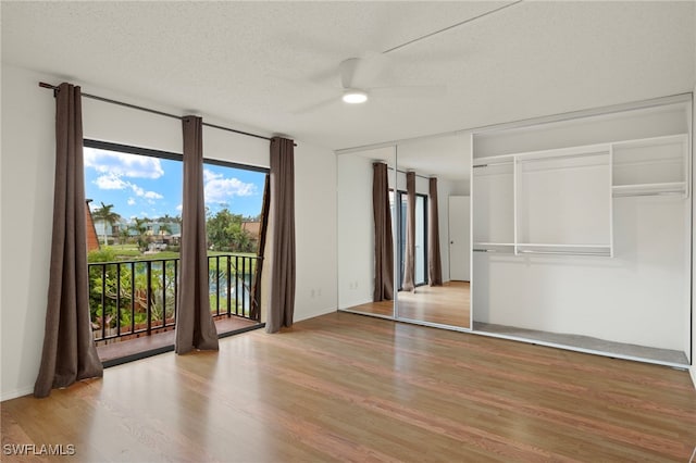 empty room with a textured ceiling, wood finished floors, and a ceiling fan