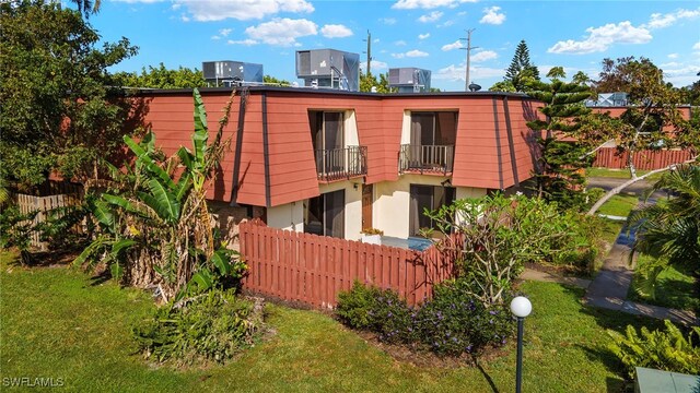 rear view of house featuring central AC, fence, and a balcony