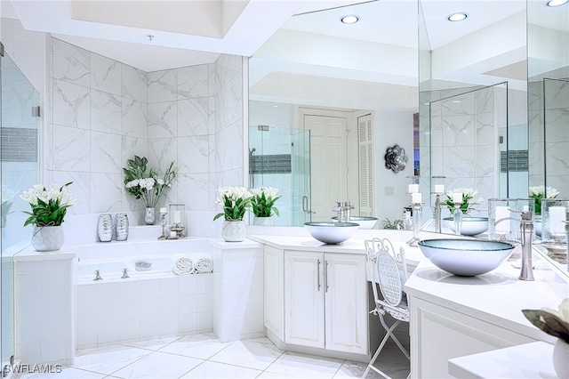 bathroom featuring vanity, independent shower and bath, and tile walls