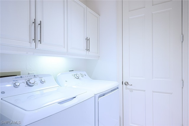 laundry room featuring washing machine and clothes dryer and cabinets