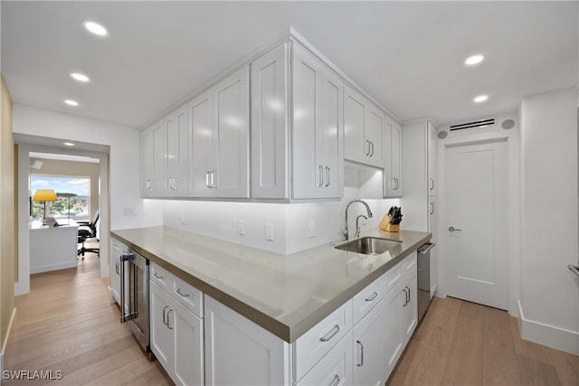 kitchen with white cabinets, sink, and light hardwood / wood-style flooring