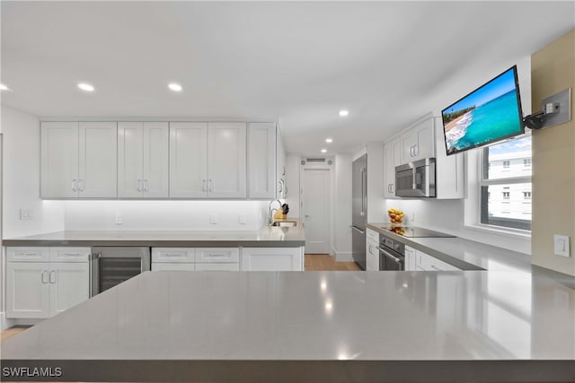 kitchen with wine cooler, white cabinetry, appliances with stainless steel finishes, and sink