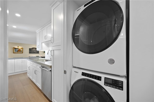 laundry area with light hardwood / wood-style flooring, sink, and stacked washer and clothes dryer