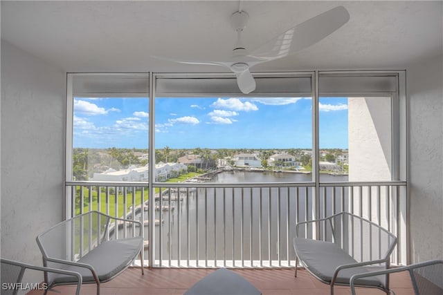 sunroom / solarium featuring a water view and ceiling fan