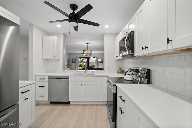 kitchen featuring light hardwood / wood-style flooring, white cabinets, sink, pendant lighting, and stainless steel appliances