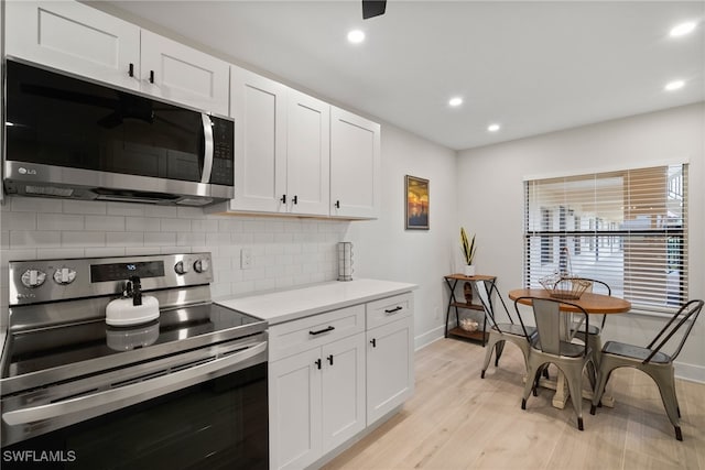 kitchen with white cabinets, stainless steel appliances, and light wood-type flooring