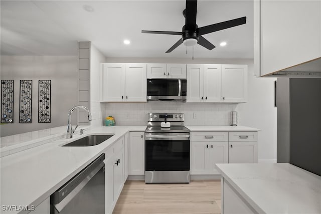 kitchen featuring white cabinetry, sink, appliances with stainless steel finishes, light hardwood / wood-style floors, and backsplash