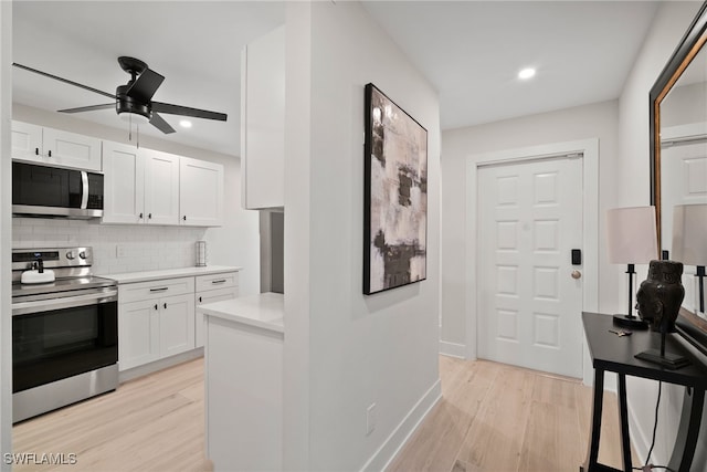 kitchen with white cabinets, backsplash, stainless steel appliances, and light hardwood / wood-style floors