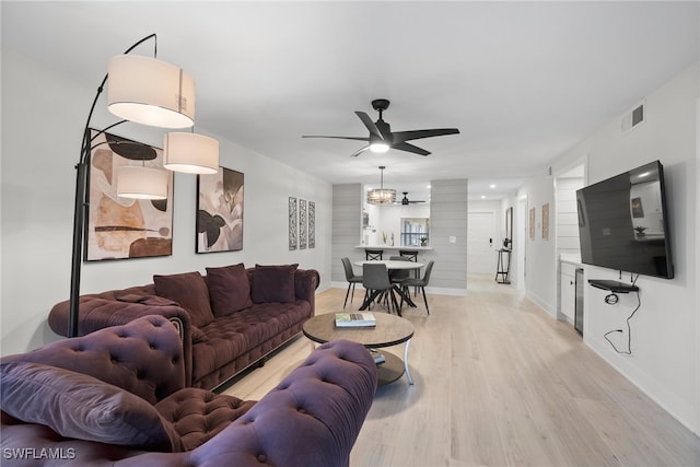 living room with ceiling fan with notable chandelier and light wood-type flooring