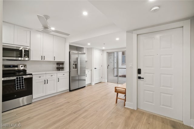 kitchen with decorative backsplash, light wood-type flooring, stainless steel appliances, ceiling fan, and white cabinetry