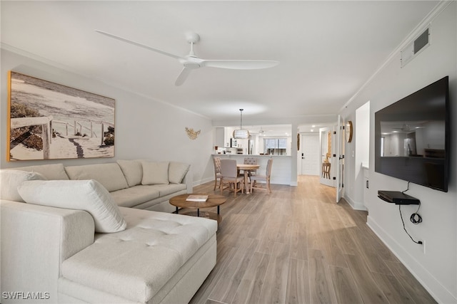 living room with ceiling fan, ornamental molding, and hardwood / wood-style flooring