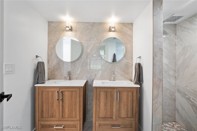 bathroom with vanity, a tile shower, and tile walls