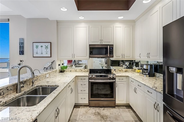 kitchen featuring white cabinetry, sink, stainless steel appliances, and light stone counters