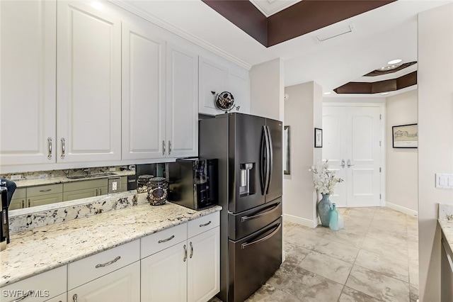 kitchen with light stone countertops, white cabinetry, ornamental molding, and a tray ceiling