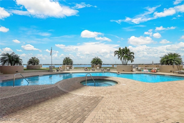 view of pool featuring a water view, a patio, and a hot tub