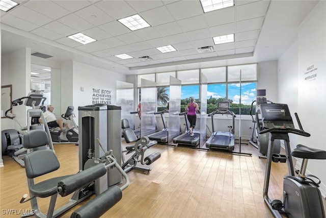 workout area with a paneled ceiling and light hardwood / wood-style flooring